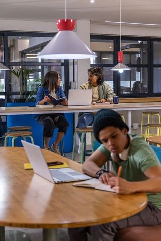 Diverse young professionals collaborating in modern coworking space with hispanic man writing