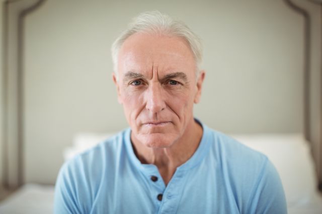 This image shows a senior man sitting at home, looking worried and thoughtful. Ideal for use in articles or advertisements related to aging, mental health, senior care, and lifestyle topics. Can be used to depict emotions such as concern, contemplation, and introspection.