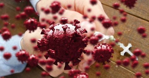 Hands holding cross surrounded by virus, symbolizing hope and faith