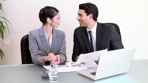 Colleagues Collaborating on Project with Laptops and Documents