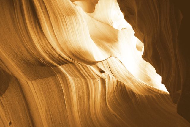 Dramatic sunlight filters through the curves of a sandstone canyon, highlighting its stunning textures and formations. This captivating scene showcases the natural beauty and geological wonders of desert landscapes. Ideal for promoting travel, adventure, geology, and nature exploration content.