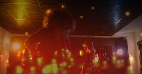 Backlit rock trio performing in intimate club with dramatic bokeh haze and moody silhouette