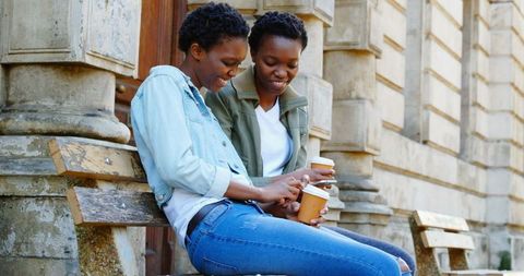 Twin Sisters Enjoying Coffee and Smartphone in Urban Outdoors