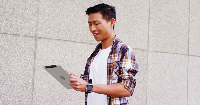 Young Man Working on Tablet Against Concrete Wall - Download Free Stock Images Pikwizard.com