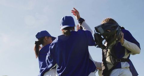 Female baseball players celebrating victory on sunny field
