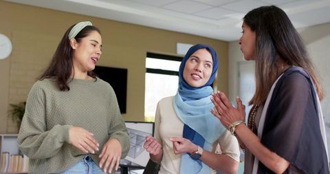 Multicultural women collaborating in bright office wearing hijab and casual business attire
