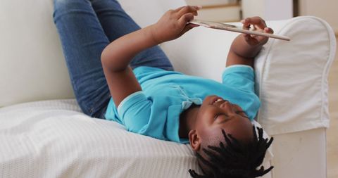 Happy African American Boy Using Digital Tablet on Couch