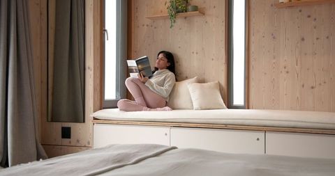 Woman relaxing with book in cozy cabin bedroom retreat