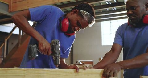 African American Coworkers Carpentry Teamwork Using Cordless Drill