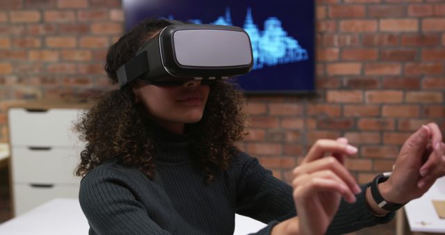 A woman wearing a virtual reality headset is engaging with a visual experience indoors. This image can be used to illustrate the adoption of new technology in various fields such as education, gaming, virtual meetings, and innovative entertainment solutions. It highlights the immersive experience and forward-thinking that come with the use of VR technology.