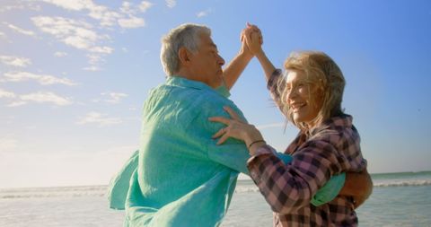 Joyful Senior Couple Dancing by Seaside