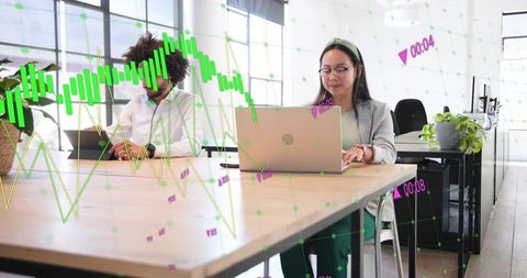 Asian woman working on laptop in modern coworking space with data visualization overlay