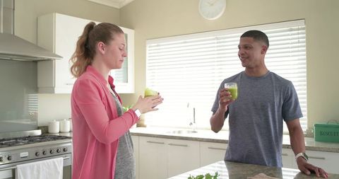 Couple enjoying green smoothies at bright modern kitchen island morning wellness