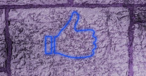 Blue thumbs up neon sign on purple stone wall texture