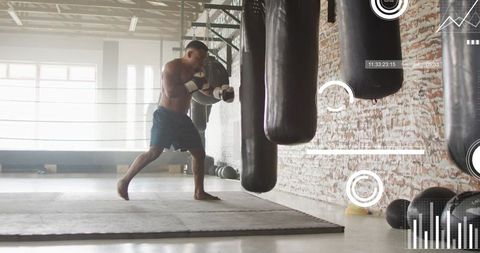Shirtless african american boxer training with heavy bags in industrial boxing gym