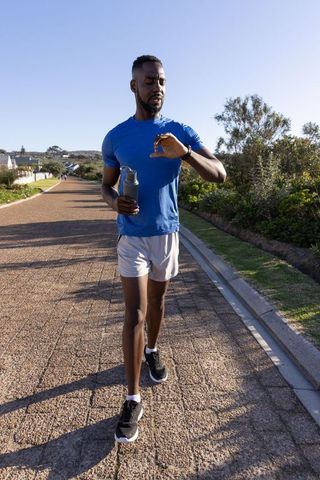 Man Jogging on Suburban Path Checking Smartwatch for Workout Tracking