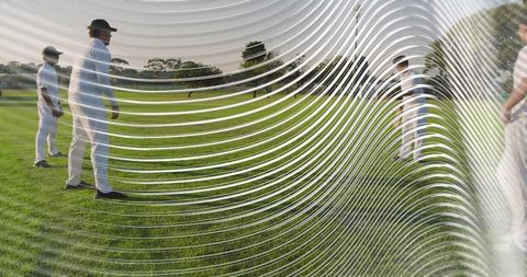 Cricket players standing on sunlit green field viewed through rippled lens distortion