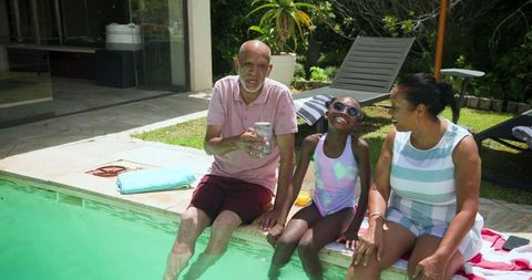 Senior Pair and Child Relaxing at Edge of Sunlit Poolside