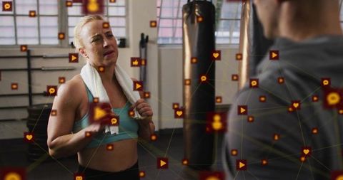 Female boxer consulting trainer in industrial gym with social media engagement overlay