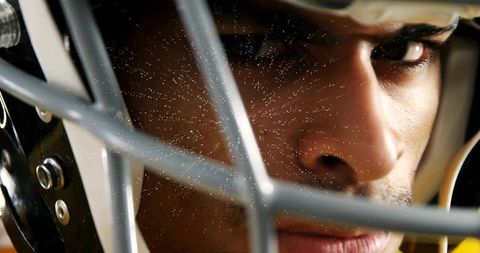 Intense closeup of football player staring through helmet facemask with focused gaze