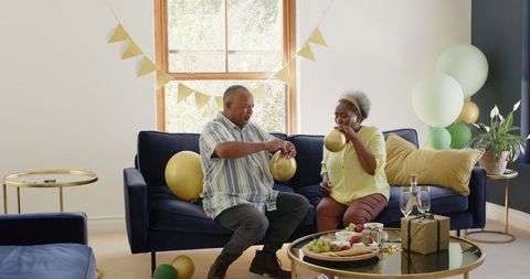 Senior Couple Preparing Living Room with Balloons for Celebration