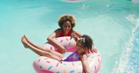 Mother and daughter enjoying pool fun with donut float
