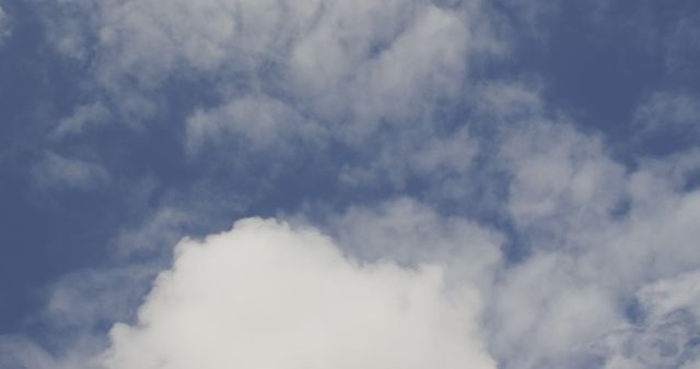 Low angle view of white and grey clouds moving across the blue sky on a windy day in fast motion