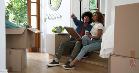 Happy couple embracing and planning in new home amid moving boxes