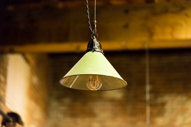 Vintage pendant light featuring an Edison bulb, providing warm illumination in a rustic setting with exposed brick walls. Ideal for interior design inspiration, creating a cozy ambiance in restaurants, cafes, and home interiors. Excellent for themes encompassing industrial decor, loft-style aesthetics, and retro elements.