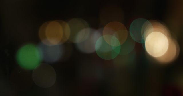 Close up of multiple moving and flickering colorful spots of yellow, green and blue bokeh street lights in a city in the evening.