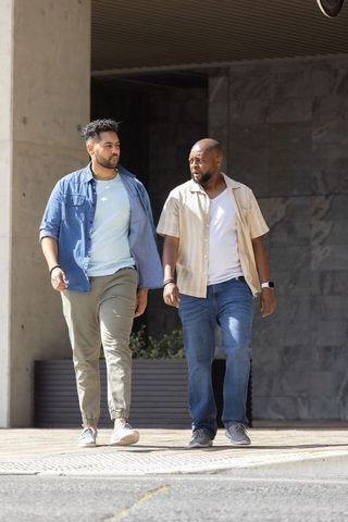 Two male friends walking city sidewalk, african american companionship, casual urban stroll