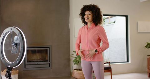 African american fitness instructor filming live home workout with ring light smartwatch