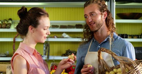 Friendly grocery assistant helping customer choose fresh produce