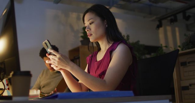 Image of asian woman using smartphone, working late in office. Business and working in office at night with technology concept.
