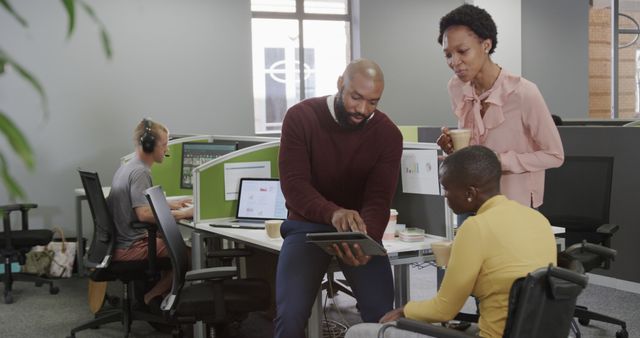 Three african american female and male colleagues using tablet and discussing in office. Casual business, teamwork, communication and office, unaltered.