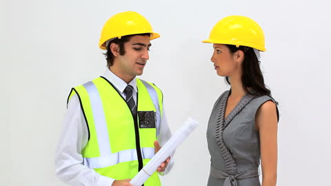 Engineers Discussing Plans Wearing High-Visibility Vests and Hard Hats