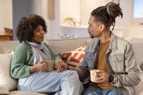African american couple holding hands drinking coffee sofa enjoying cozy intimate conversation