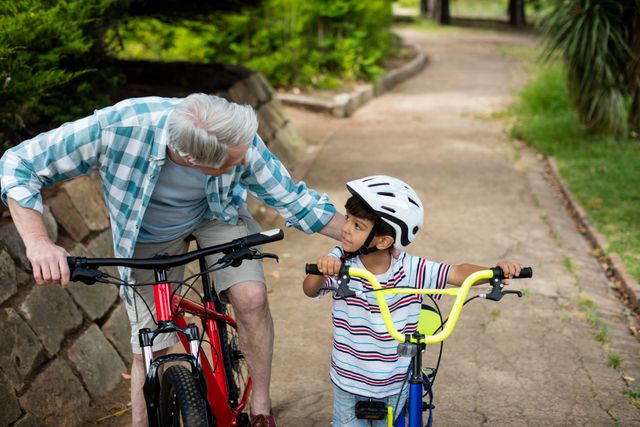 Grandfather and grandson standing with bicycle in park - Download Free Stock Photos Pikwizard.com