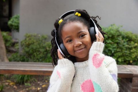 Young girl enjoying music outdoors in cosy sweater