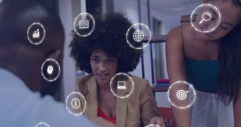 Businesswomen collaborating and presenting digital strategy with virtual icons in modern office