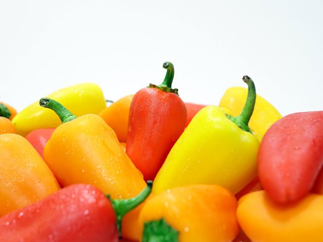 Colorful mini bell peppers showcased on a white background magnify their freshness and vibrancy. Perfect for use in food blogs, cooking websites, healthy eating articles, nutrition presentations, and grocery advertising. The image emphasizes the bright, natural colors of the vegetables, making them appear appetizing and nutritious.
