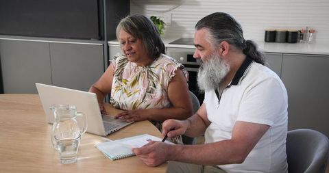 Senior Couple Using Laptop at Home Engaged in Discussion