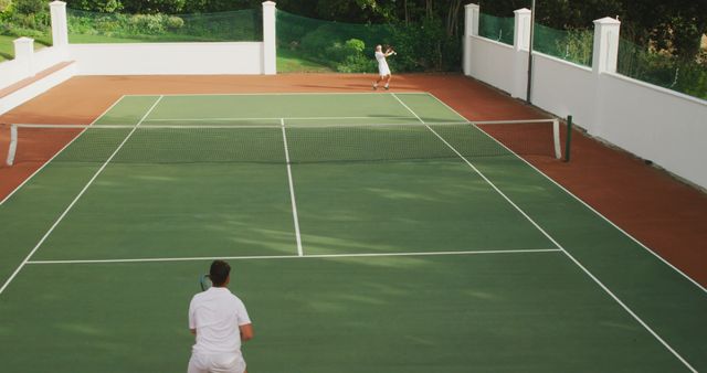 Two players competing in a tennis match on an outdoor court. Ideal for use in advertisements promoting sports equipment, fitness clubs, or active lifestyle tips and blogs.