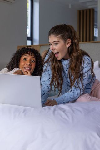 Diverse Friends Rejoicing with Surprise at Laptop in Cozy Bedroom
