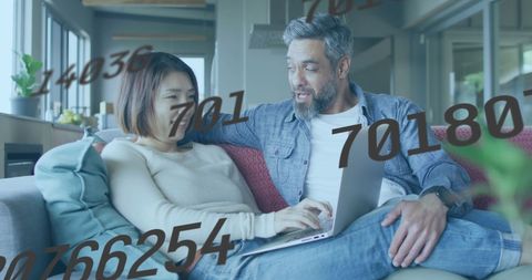 Diverse Couple Analyzing Data with Laptop at Home