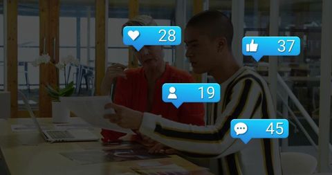 Creative team reviewing print designs at modern office desk with social media alerts