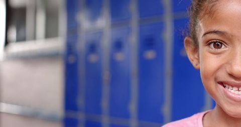 Smiling Young Girl with Blue Lockers in School Corridor