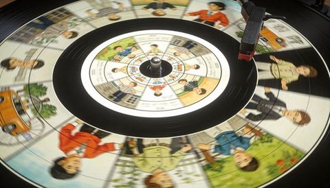 Spinning vinyl record with family cartoon panels on turntable and red stylus on grooves