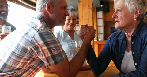 Friendly Arm Wrestling Between Senior Woman and Middle-Aged Man