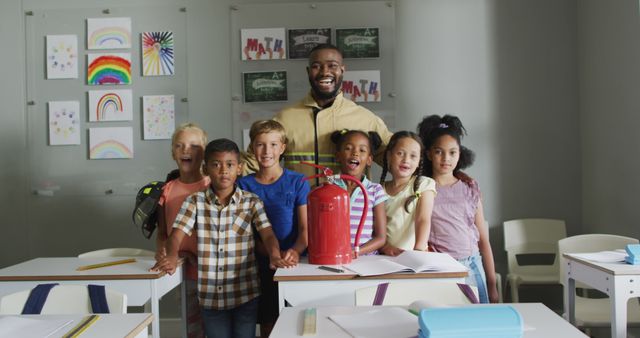 This image depicts a happy teacher standing with a diverse group of students in a modern classroom. They are all smiling and holding a fire extinguisher, emphasizing safety education. The colorful artwork on the walls and the bright atmosphere suggest a vibrant learning environment. Ideal for use in educational materials, school brochures, safety training guides, and promotional content showcasing school diversity and proactive learning initiatives.
